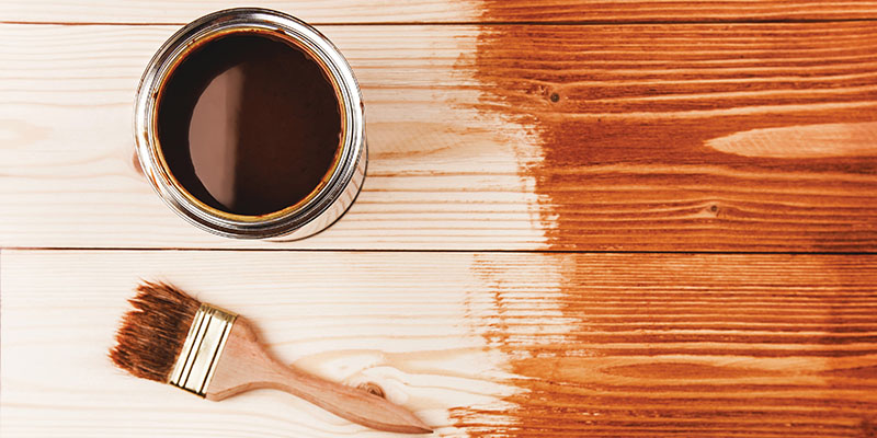 A paintbrush and a paint on a wood surface